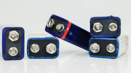 Five blue used, chaotically laid out and scattered PP3 batteries on a white background with...