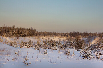 Lost in Siberia. Northern landscape. Snow-covered hills and ravines, overgrown with coniferous forest and covered with snow.