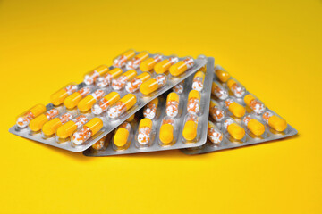 Capsules in a blister. Medical tablets, vitamins in a granule, in yellow capsules on a yellow background. blur as a creative idea of the author, close-up