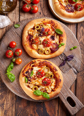 Mini Pizza with tomatoes, chicken, red onion, olives and mozzarella cheese. Delicious homemade pizzetta. Italian cuisine.