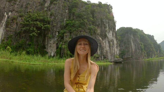 A young woman on a boat having a river trip among spectacular limestone rocks in Ninh Binh, a tourist destination in northern Vietnam. Travel to Vietnam concept