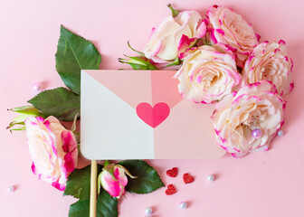Obraz na płótnie Canvas envelope, valentine's letter and delicate bouquet of bushy peony roses and pearls on a pink background, the concept of congratulations on Valentine's day