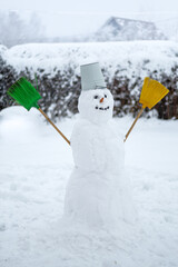 Portrait of a happy white snowman with an orange carrot nose, black embers for eyes, brooms for...