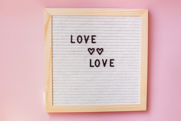 The inscription love on a gray board. Happy Valentine's Day. Pink background