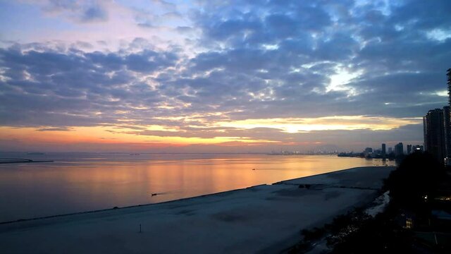 Time lapse sunrise with moving cloud at Penang Gurney Drive overseeing the sea front with ships