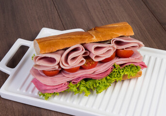 Bocadillo tipo emparedado con tomates rojos y verduras.
