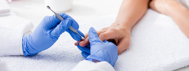 partial view of manicurist making manicure to client with cuticle pusher, banner