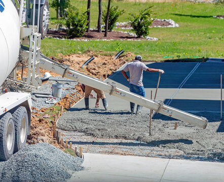 Unidentifiable Hispanic Men Working On A New Concrete Driveway At A Residential Home, Focus On Concrete Chute