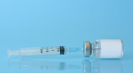Vaccine in a bottle with a syringe on a blue background.The concept of medicine, healthcare and science.Coronavirus vaccine.Copy space for text.