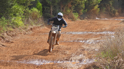 Zoom photo of professional motocross rider on his motorcycle on extreme dirt and mud terrain track. Biker flying on a motocross motorcycle.