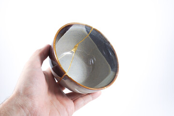 Kintsugi gray pottery. Gold cracks restoration on old Japanese  wabi sabi ceramic.