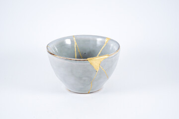 Kintsugi gray pottery. Gold cracks restoration on old Japanese  wabi sabi ceramic.