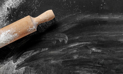 Dark food background with flour. Top view black board with rolling pin and flour. Space for text, template and mockup.
