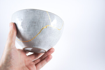 Kintsugi gray pottery. Gold cracks restoration on old Japanese  wabi sabi ceramic.