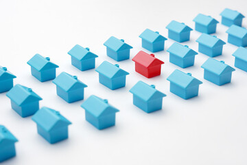Fototapeta na wymiar Real estate and property market in cottage village. Mortgage and buying a house. Red miniature house model among blue toy houses arranged in three rows different from group of same type miniature home