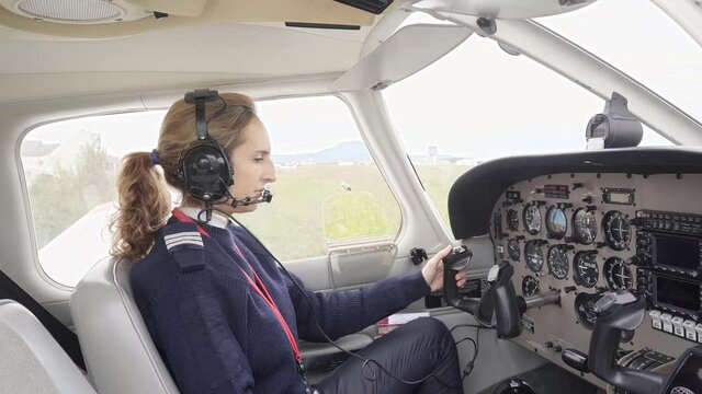Side view of a female pilot in the cockpit of an airplane.