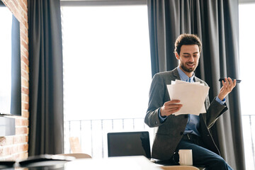 Pleased businessman talking on mobile phone while examining documents