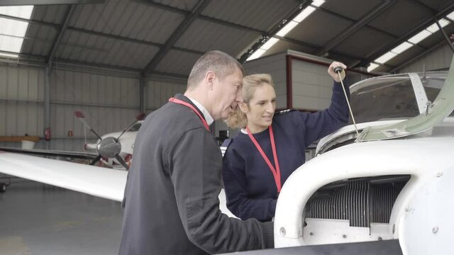 Female flight instructor teaching her student how to do the maintenance of the plane.