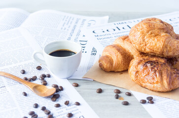 Close Up of Fresh Baked Croissant on wood table with Coffee Mug and  news paper on Relaxing Morning at Home, Bread and coffee, breakfast Healthy food of the city life