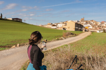 una ragazza si riposa e beve dell'acqua poco prima di arrivare ad un piccolo paese lungo il cammino...