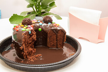 Chocolate cake with brigadeiro topping and colorful chocolate pieces.