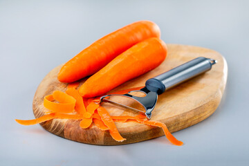 Peeling fresh carrot with peeler. Vegetables for a healthy diet. Cooking healthy raw food.