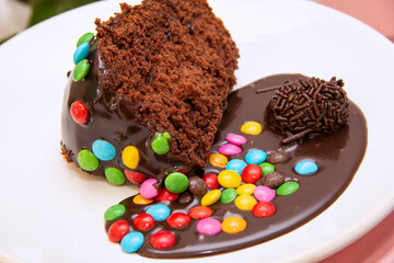 Piece of chocolate cake with brigadeiro topping and colorful chocolate pieces