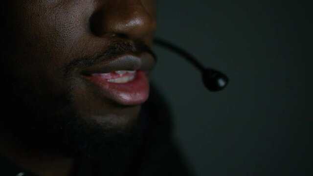 Close up of mans mouth talking through a headset int eh dark at night