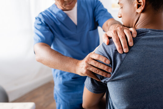 chiropractor working with injured arm of african american patient on blurred foreground