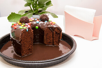 Chocolate cake with brigadeiro topping and colorful chocolate pieces.