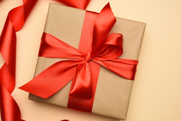 square gift box is packed in red paper and curled silk ribbon, festive background