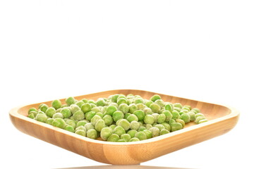 Ripe frozen green peas on a bamboo plate, close-up, isolated on white.