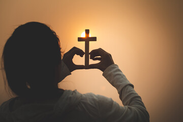 A woman holding a cross symbolizes the heart. Backdrop the sun Christian religious concept, the...