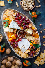 Big plate with appetizer assortment. Grape, cheese, nuts, jam and bread.