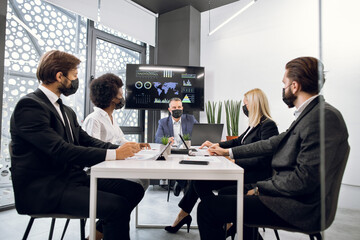 Business concept in terms Covid-19 pandemic. Multiethnic focused businesspeople with face masks,...