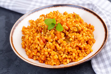 Traditional turkish bulgur pilaf with tomato sause in plate