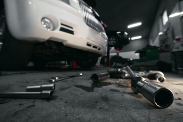 Heads and socket wrench, tool scattered on the floor. Vehicle in the background. Car service. Selective focus.