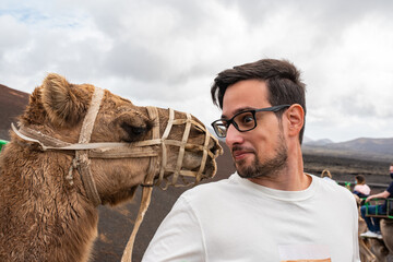 Young man making a funny face of surprise when posing next to a camel while on a sightseeing tour