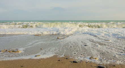 Sea wave at the sandy beach on a summer day.