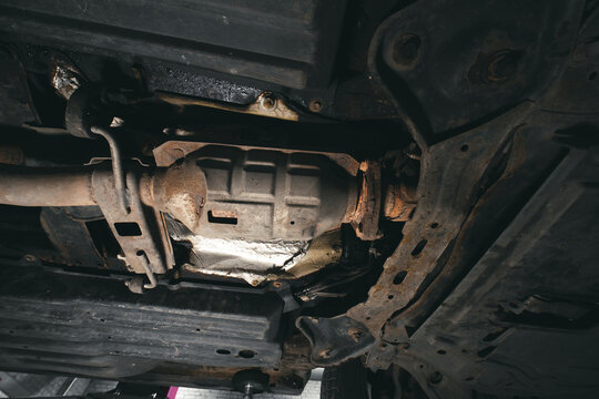 Close-up on the part of the bottom of the car from the front of the exhaust pipe and the catalyst disassembled during the repair in the workshop auto service vehicles