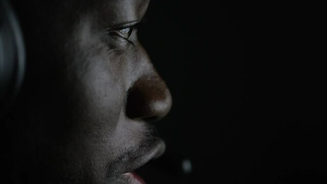 Close up facial shot of young man playing video games and chatting through his gaming headset