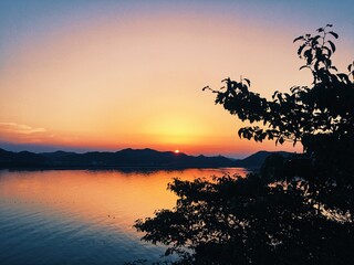 Fototapeta na wymiar Silhouette Tree By Lake Against Sky During Sunset