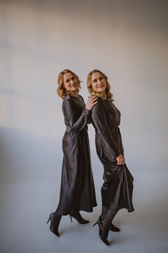 Beautiful Two Blonde Middle Aged Twin Sisters In Gray Dresses Hugging Each Other Together