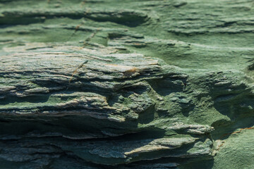 Turquoise green rock, natural stone off the coast of Folegandros island. Greece.