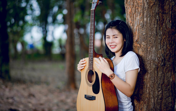 Girl and his guitar Happily hug the guitar, standing in the woods, open air, fresh music