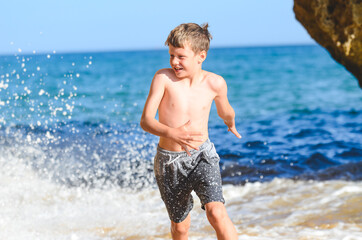 Fototapeta na wymiar Happy young child running through sea waves.