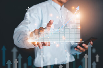 Double exposure of Asian man wearing a blue shirt Using a pen to point at the virtual screen of the upcoming 2021 stock chart. Business Trading concept.
