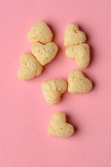 Macro photo of dry breakfast made of wheat or oats in the heart shape on pink background