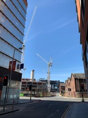 Construction cranes in Manchester City centre with a clear blue sky background. 