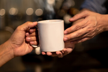 Close up of hand's barista giving coffee cup to customer's hand.